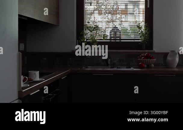 Warm under-cabinet lighting turns on in a modern kitchen at morning ...