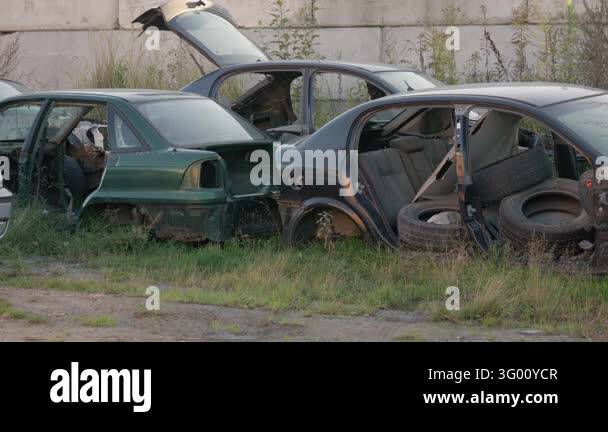 Dismantled car body shells sit abandoned outdoors at an automotive ...