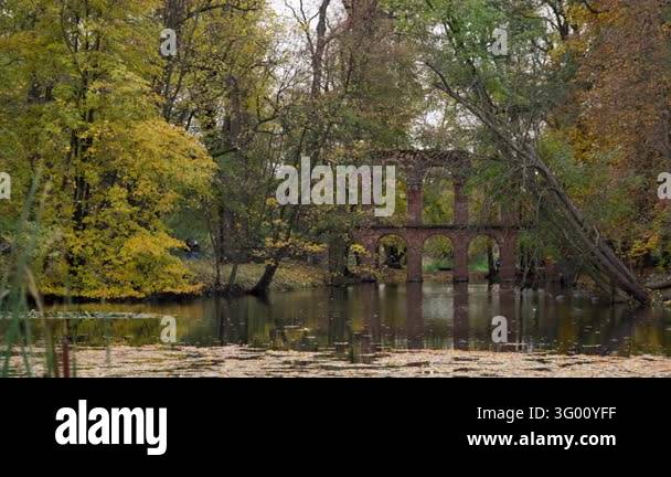 Historic brick aqueduct ruins stand across autumn pond in Arkadia Park ...