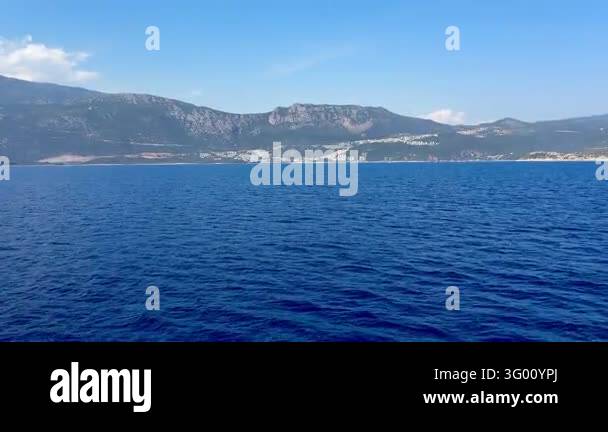 A coastal view of a town nestled between mountains and the sea. The ...