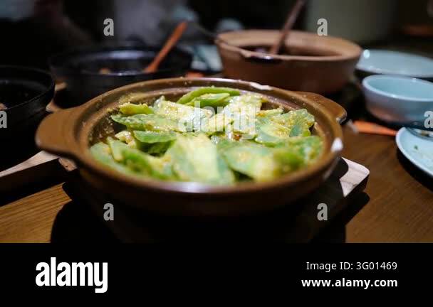 Close-up of a steaming bowl of green vegetables in a savory sauce ...