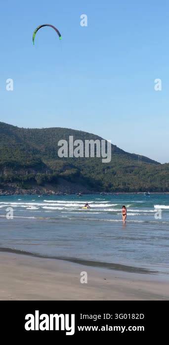 Vertical coastal scene with wet sand, shallow reflective surf, standing ...