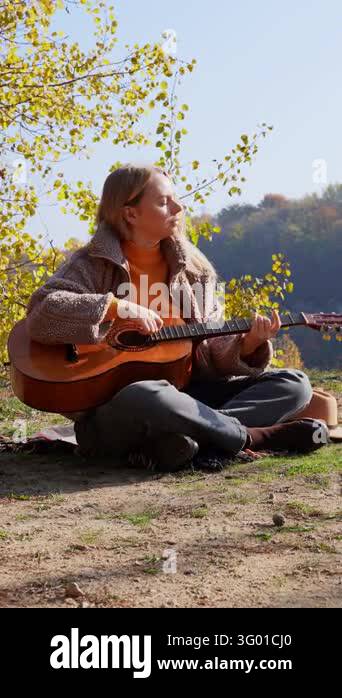Instrument Land Beautiful blonde girl playing acoustic guitar and singing relaxing ...