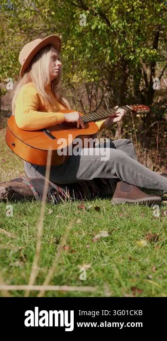 Instrument Land Beautiful blonde girl playing acoustic guitar and singing relaxing ...