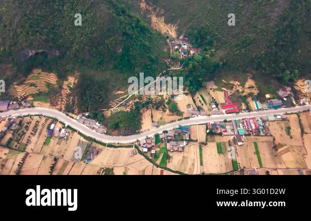 An aerial view follows a road through a village and patchwork fields ...