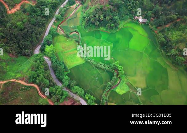 A drone follows a winding road through Ha Giang Vietnam passing green ...