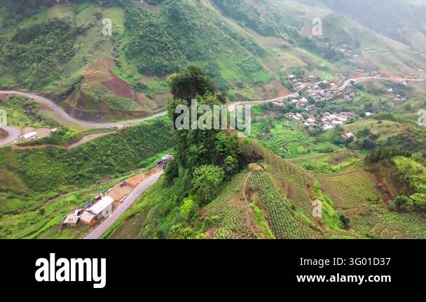 An aerial view follows the Ha Giang Loop road through mountain slopes ...