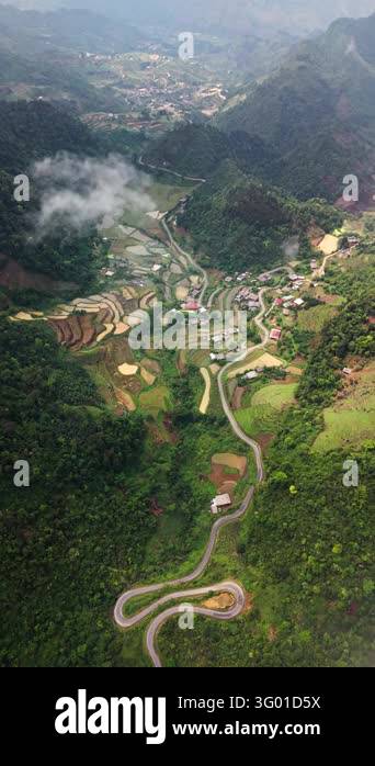 An aerial view moves over a winding road village and fields in the Ha ...