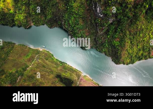 An aerial view follows a river through forested hills and fields along ...