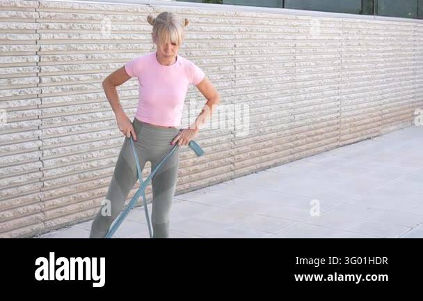 An athletic woman in pink top and grey leggings works out with ...