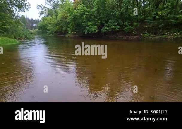 Scenic landscape of a wide river during rain looking down the flow with ...