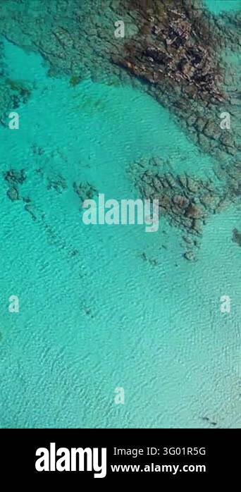 Vertical aerial top down view of turquoise sea water splashing over ...