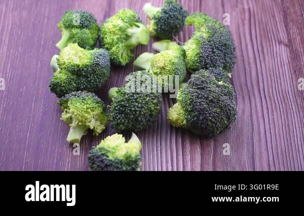 Close up view of raw fresh green broccoli florets in metal bowl and on ...