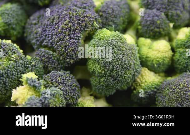 Close up view of raw fresh green broccoli florets in metal bowl and on ...