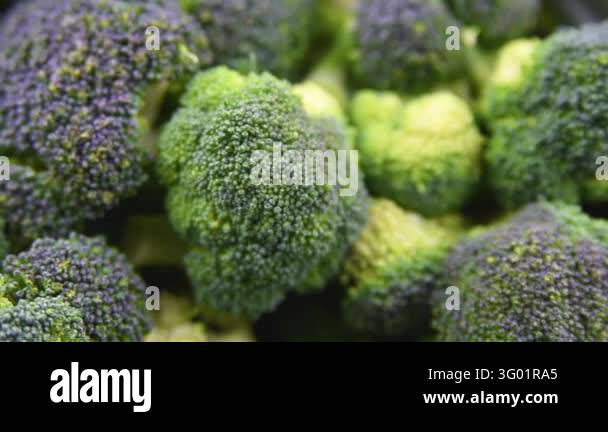 Close up view of raw fresh green broccoli florets in metal bowl and on ...
