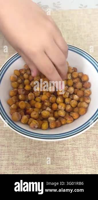 Smlll Image Close up view of small child hand picking up roasted crispy chickpea ...
