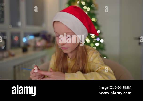 Girl wearing red hat and yellow sweater spreads icing on gingerbread ...