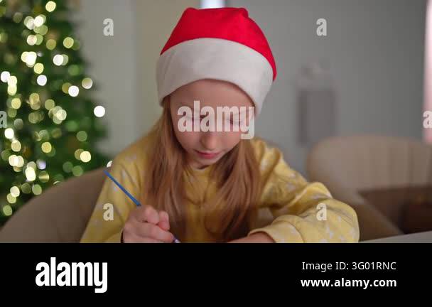 Girl wearing red hat and yellow sweater spreads icing on gingerbread ...
