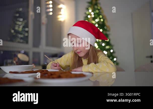 Girl in Santa hat carefully places iced gingerbread cookies on glossy ...