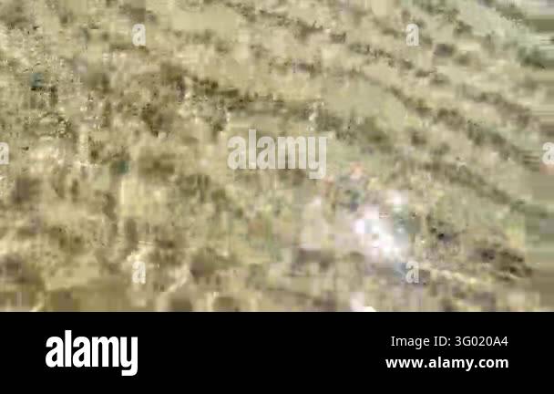 Gentle golden waves ripple over a sandy seabed, producing layered ...