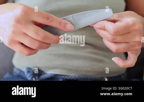 Woman maintaining natural fingernails with a file during a home beauty ...