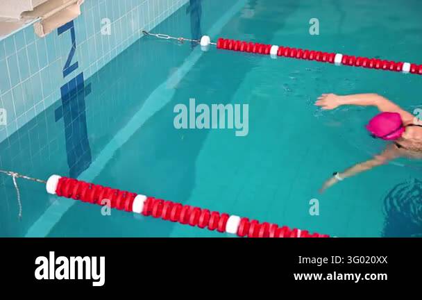 Pool Wiver Woman performs backstroke turn in swimming pool near wall. Sport video ...