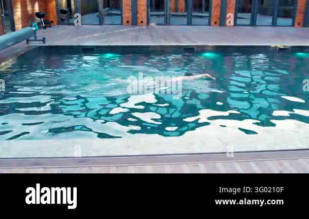 Outdoor pool scene with woman swimming freestyle crawl at twilight ...