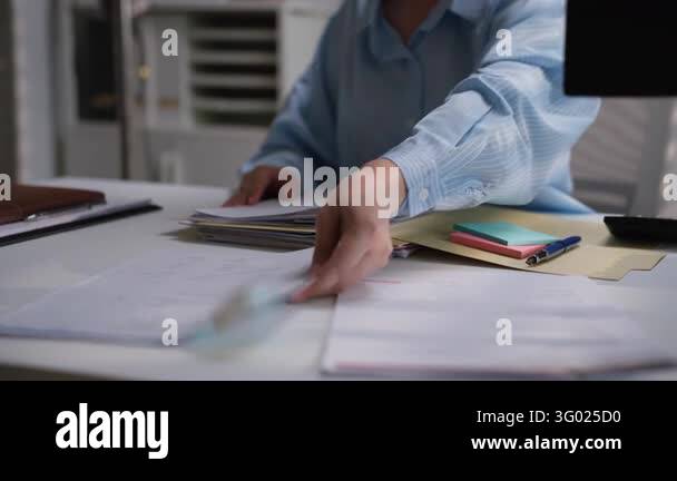 Office worker organizing a stack of printed financial documents with ...