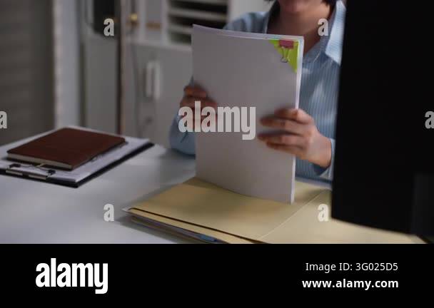 Office employee sorting financial paperwork inside a folder with ...