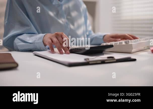 Asian businesswoman using calculator to calculate budget figures while ...