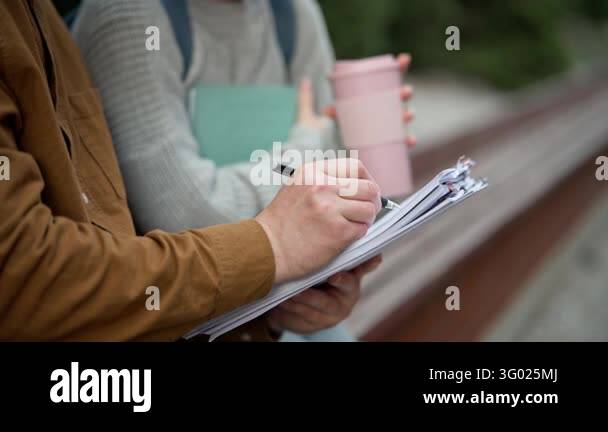 Checklist Writing Image Students writing notes on clipboard while holding coffee cup outdoors ...