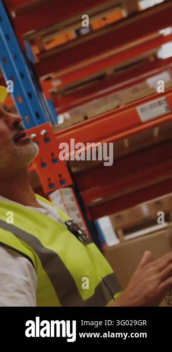 Vertical video: Warehouse man scanning racks, checking stock, pointing ...