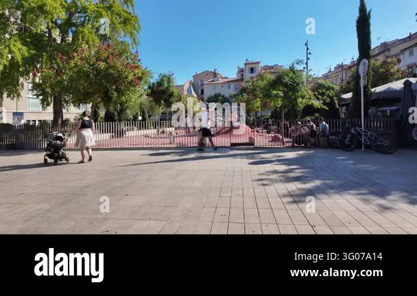 France Tree Antibes, France - September 15, 2026 - Sunny urban square with a fenced ...