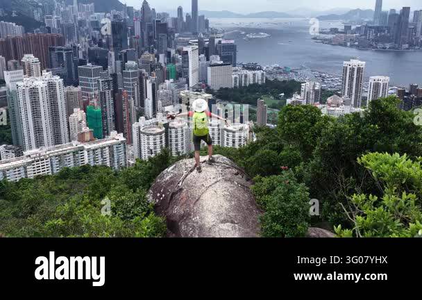 Aerial view of a person standing on a rock with arms outstretched ...