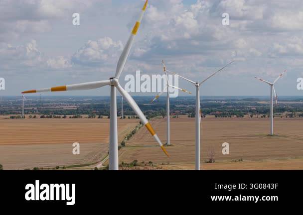 Power Generations Close-up aerial view wind turbines rotate above harvested farmland ...