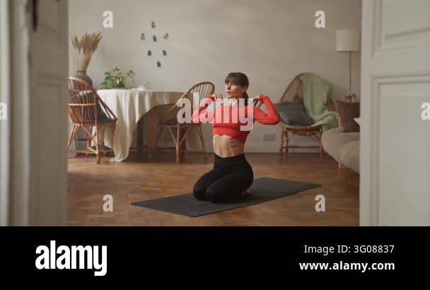 Side view of focused girl in orange top doing stretching and warming up ...