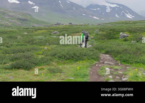 A person with a large backpack walks along the Kungsleden trail in ...