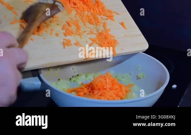 Kitchen Cook Using Spoon a cook using a wooden spoon to slide fresh shredded carrots from a ...