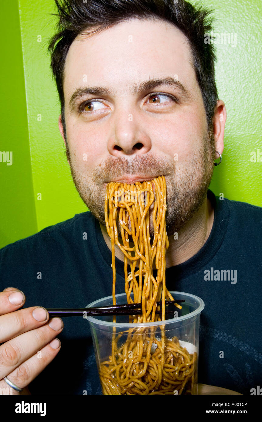Man eating noodles with chopsticks Stock Photo