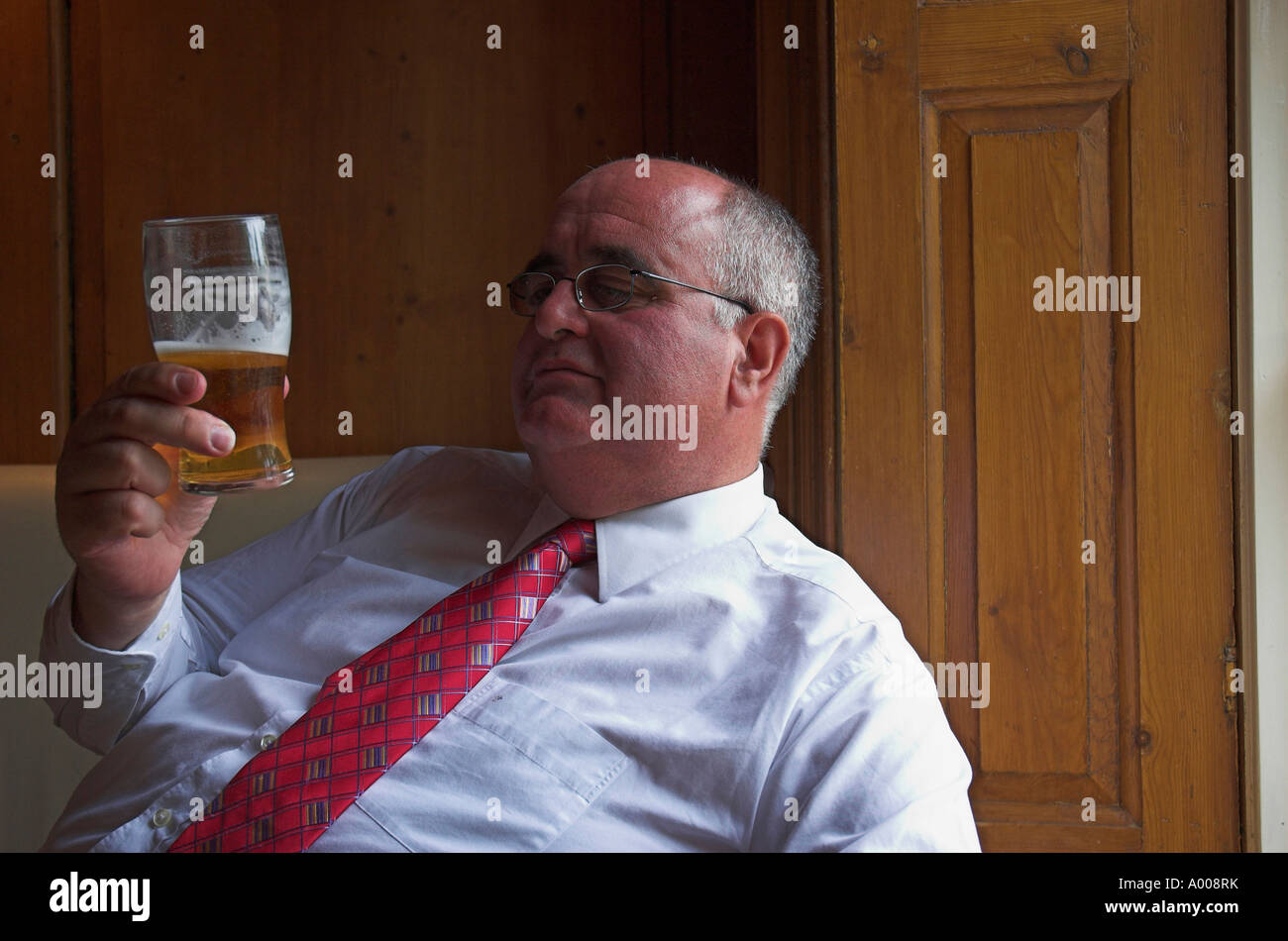 Mature man in the pub contemplating a pint glass half full or half empty of beer. UK Stock Photo
