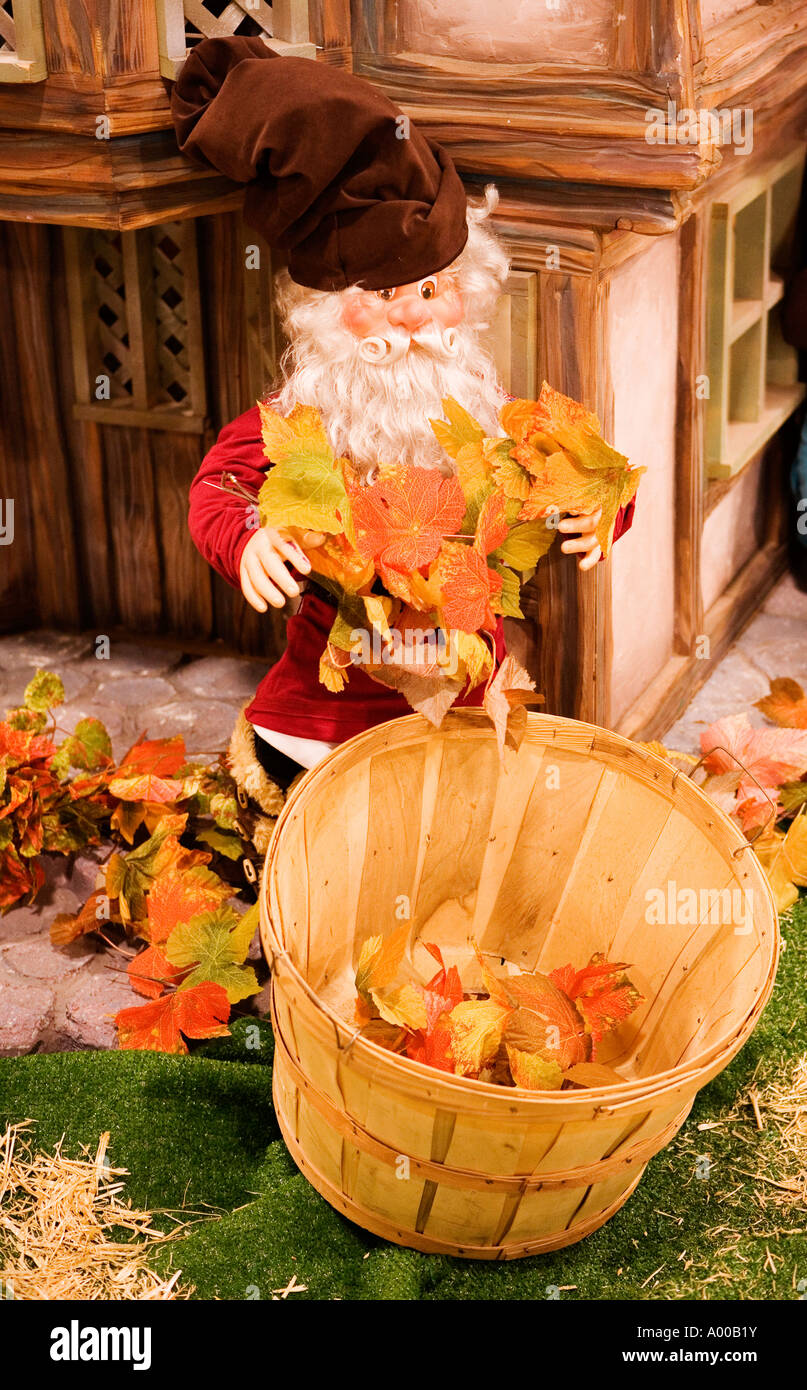 Image of an Elf Like creature gathering colorful maple leaves and putting them into a wooden barrel Stock Photo