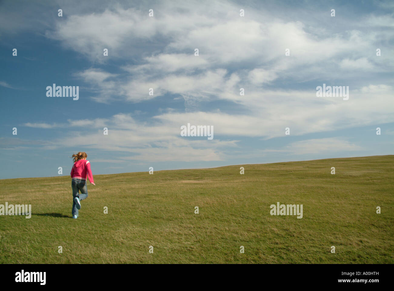 girl running across green grass into the sky Stock Photo Alamy