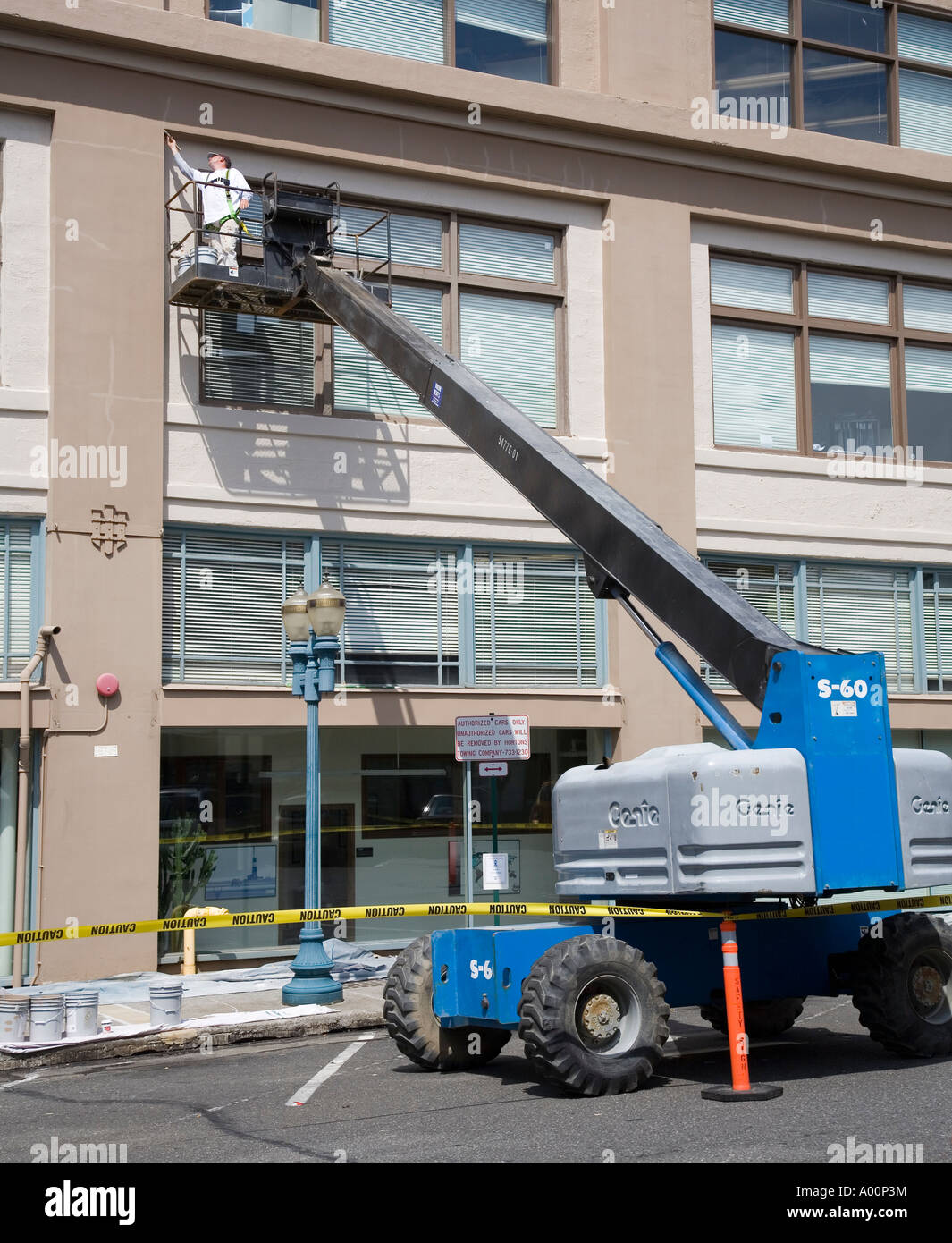 Man using safety harness and mobile crane to paint building Bellingham Washington state USA