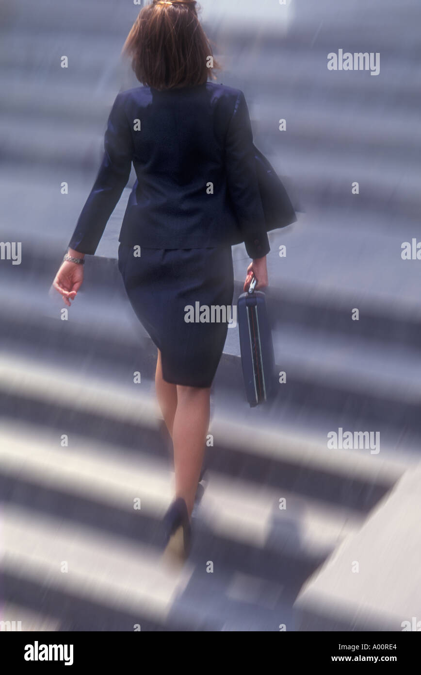 businesswoman walking up steps to office with brief case Stock Photo