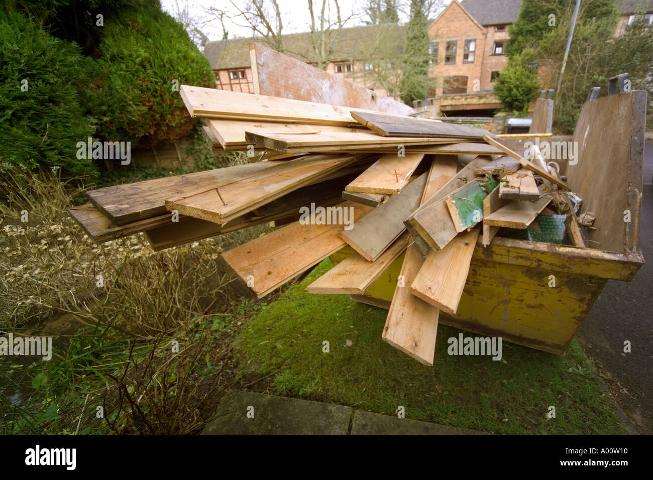 skip full of discarded wood outside house being converted Stock Photo