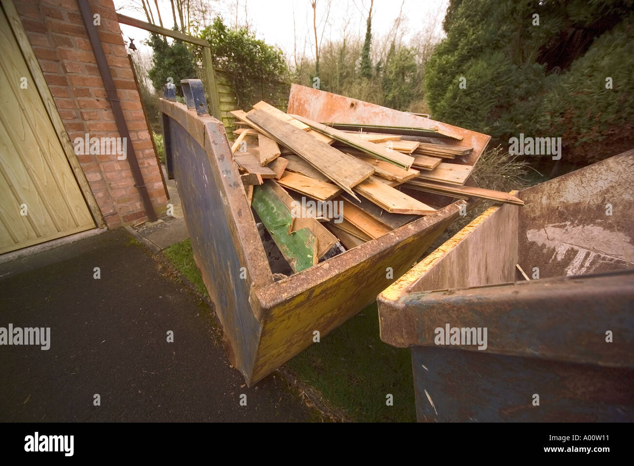 skip full of discarded wood outside house being converted Stock Photo