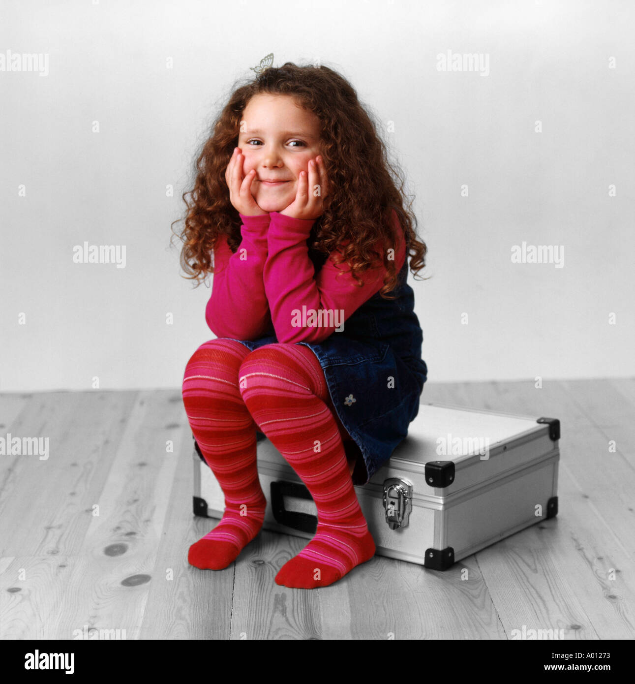 Girl smiling sitting on metal case Stock Photo