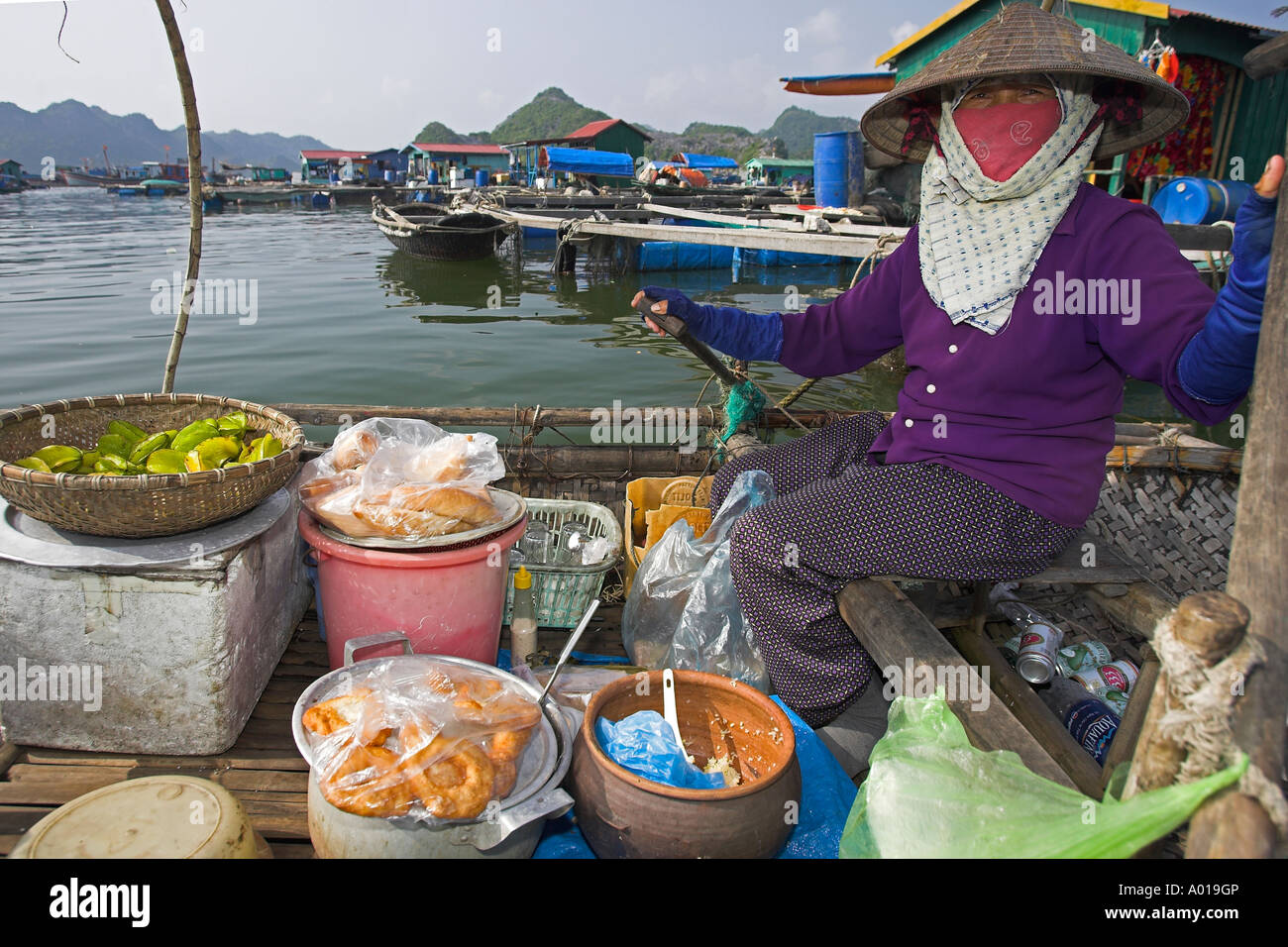Woman selling bread doughnuts fruit and drinks rows her shop around floating fishing village Cat Ba Town bay north east Vietnam Stock Photo