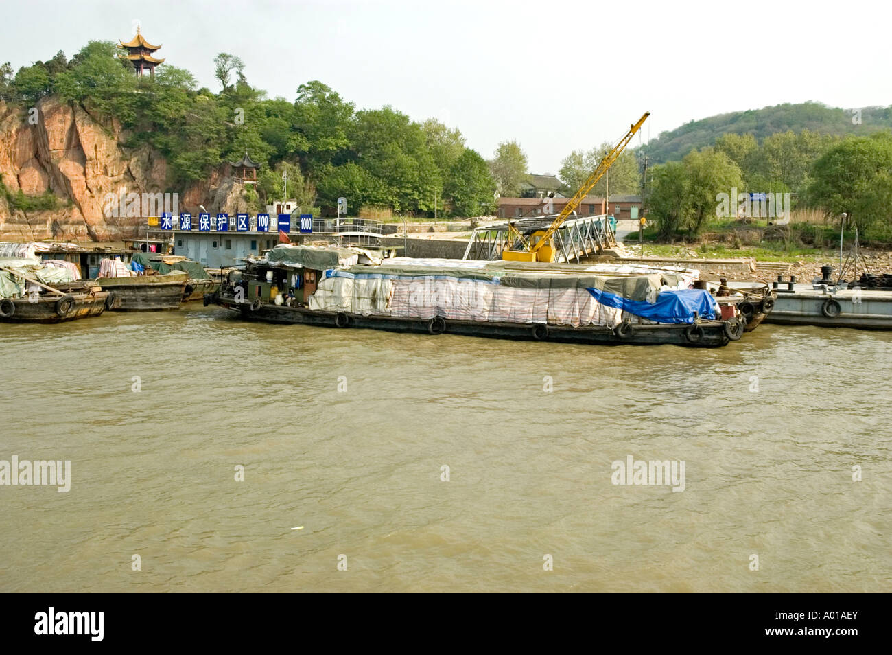 Chinese barges with their cargo covered for protection moored to a dock on the banks of the Yangtze river, Nanjing Stock Photo