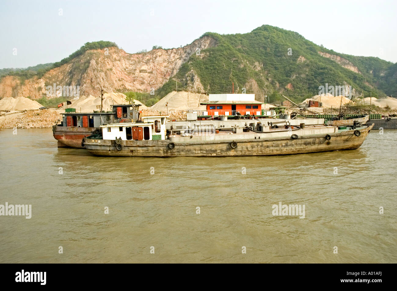 Fuel carrying barges moored to the dockside at a rock crushing plant on the banks of the Yangtze river, Nanjing, China Stock Photo